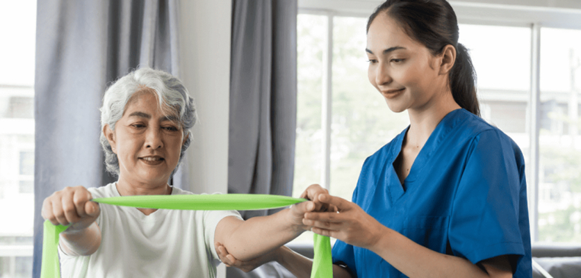 Physiotherapist guiding an elderly using resistance band exercises to improve bone strength